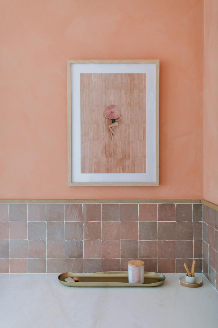 A painting on a wall painted with limewash wall paint that compliments rustic tiles in a bathroom