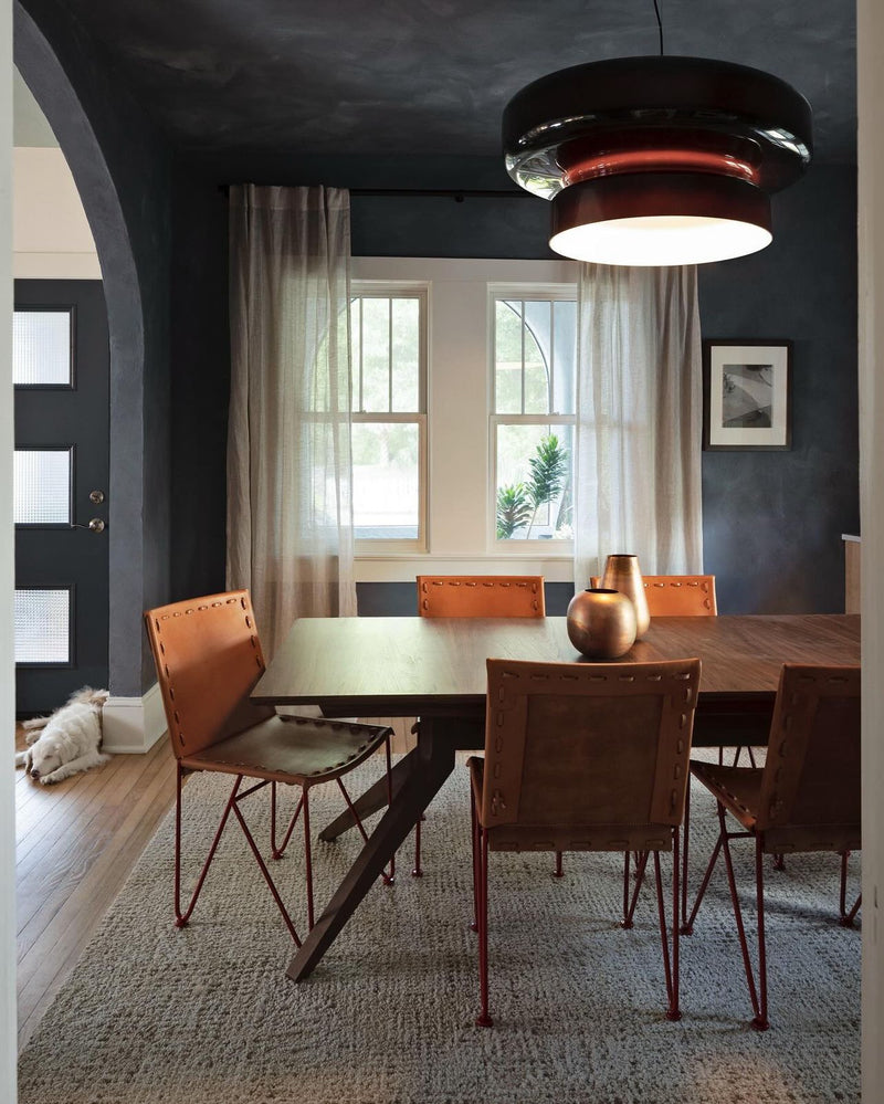 Darker dining room with orange accent chairs and walls painted with a textured limewash wall paint